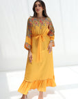 Woman wearing a yellow dress with floral embroidery on a white background