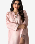 A woman modeling a light pink long-sleeve tunic or kurta with a floral print tie-neck bow and matching floral cuff accents, set against a plain light gray studio background.