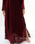 Lower hem detail of burgundy velvet jalabiya with intricate tonal embroidery