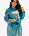 A woman modeling a turquoise blue long-sleeve kurta with a metallic silver floral pattern, holding a matching turquoise clutch bag against a light gray background.