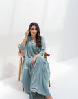 Seated full-length view of dusty blue embroidered kaftan with a relaxed flowing silhouette