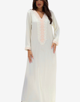 A woman modeling a long white or off-white maxi dress with a V-neckline and delicate pale pink lace detailing down the front, set against a plain light gray background.