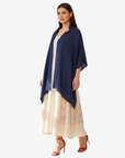 A woman modeling a navy blue shawl draped over a cream-colored printed maxi dress, set against a plain light gray background.