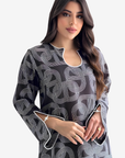 A woman modeling a black long-sleeve tunic dress with a white geometric line pattern and white piping details, set against a plain light gray background.