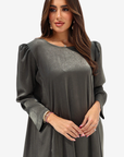 A woman modeling a dark gray long-sleeve tunic dress with textured puff sleeves and a round neckline, set against a plain light gray background.