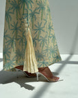 Palm Canopy Jalabiya close-up showing the pleated hem insert and teal palm print on cream linen blend fabric