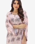 A woman modeling a light pink kurta with a gray palm tree print, featuring wide bell sleeves and a split neckline with a small gold zipper detail.
