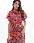 Close-up portrait of the Prism Flow Sunset Abstract Linen Blend Jumpsuit featuring the elegant draped neckline and colourful artistic print.