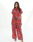 Full-length view of the Prism Flow Sunset Abstract Linen Blend Jumpsuit with relaxed silhouette and vibrant abstract sunset-inspired print.