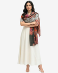 A woman modeling a cream-colored traditional dress with a draped multicolor scarf featuring orange, red, and gray paisley patterns, set against a plain light gray background.