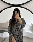 Person wearing a black and white patterned dress taking a mirror selfie.
