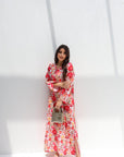 Woman wearing a floral dress holding a handbag against a white background