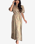 A woman modeling a midi-length beige wrap dress with puff sleeves, a self-tie waist, and a subtle multicolor abstract print, set against a plain light gray background.