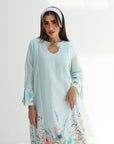 Woman wearing a light blue dress with floral patterns on a white background