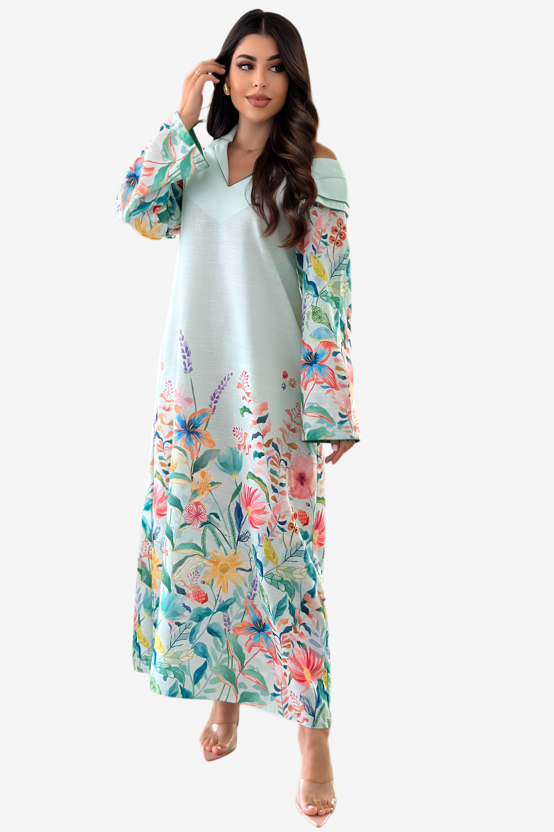 A woman modeling a long, off-the-shoulder maxi dress with a light mint green base and a vibrant multicolor floral print on the sleeves and lower skirt, set against a plain light gray background.