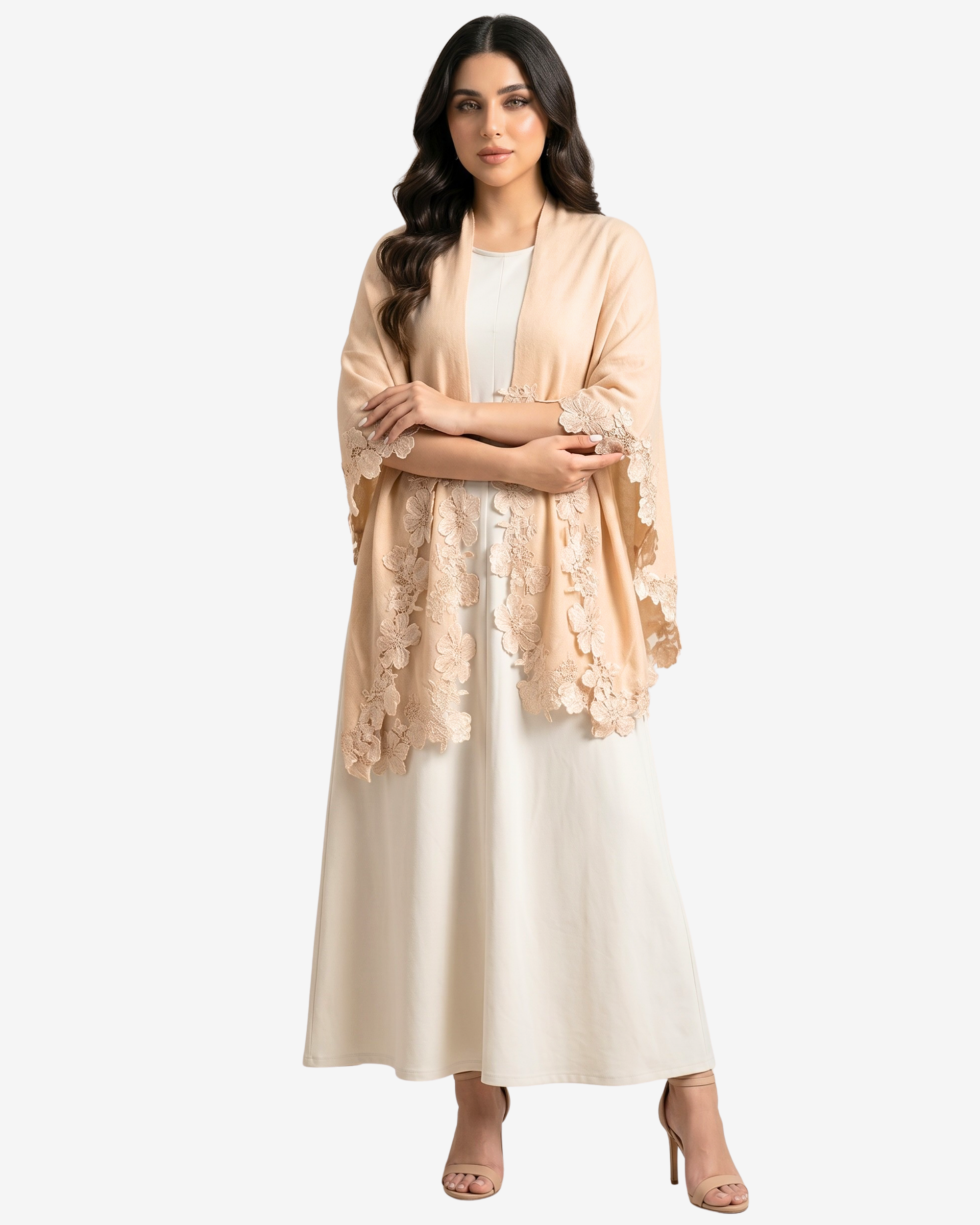 A woman modeling a light peach-beige open-front shawl or lightweight jacket with floral lace trim over a cream dress, photographed against a plain light gray studio background.