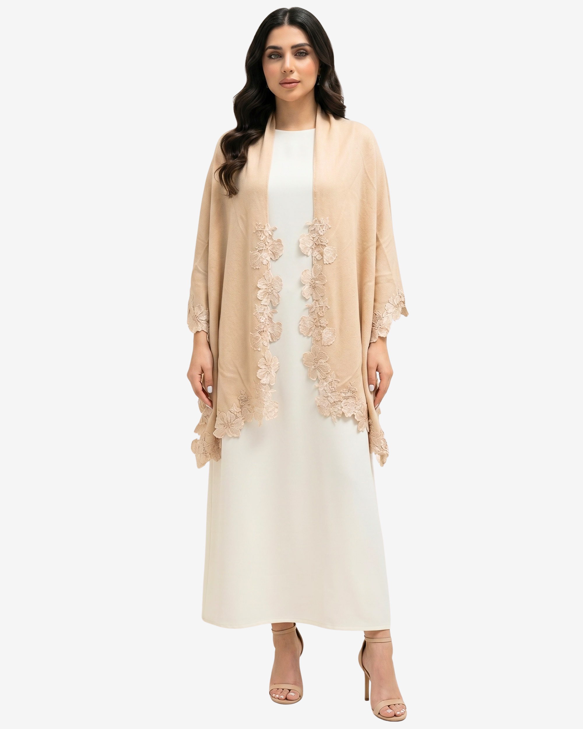A woman modeling a light beige open-front cardigan with floral lace trim over a white maxi dress, standing against a plain light gray studio background.