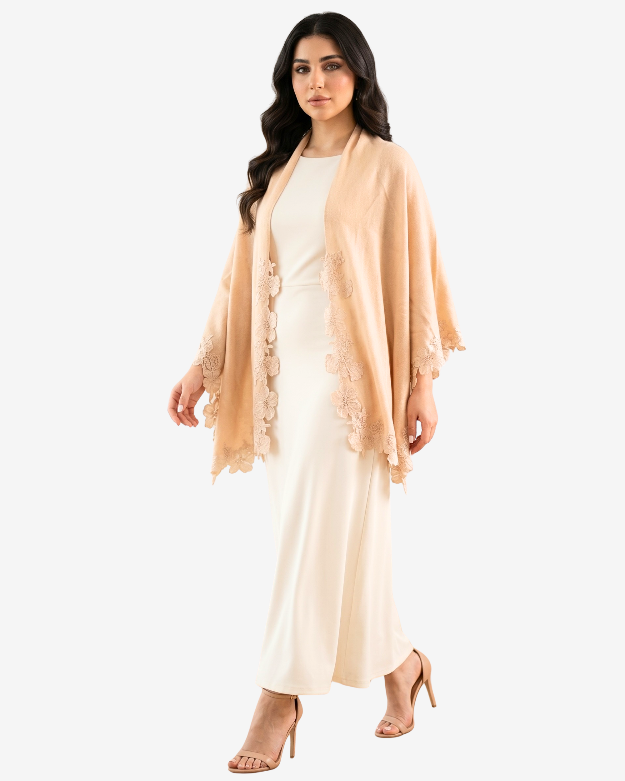 A woman modeling a light peach-beige open-front shawl or wrap with floral lace trim over a cream maxi dress, against a plain light gray studio background.