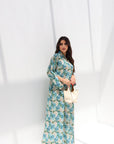 Woman wearing a floral dress holding a white bag against a white background