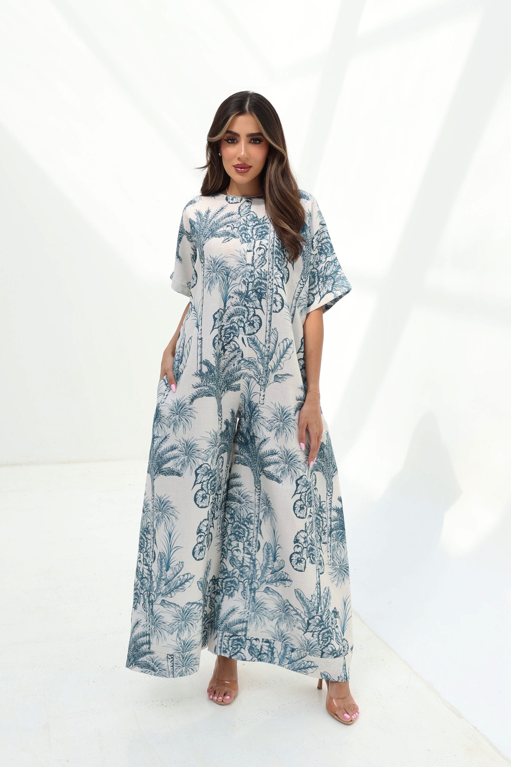 Full-length view of the Blue Tropique Linen Blend Jumpsuit featuring an ivory base, blue tropical print and comfortable wide-leg design.