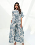 Full-length view of the Blue Tropique Linen Blend Jumpsuit featuring an ivory base, blue tropical print and comfortable wide-leg design.