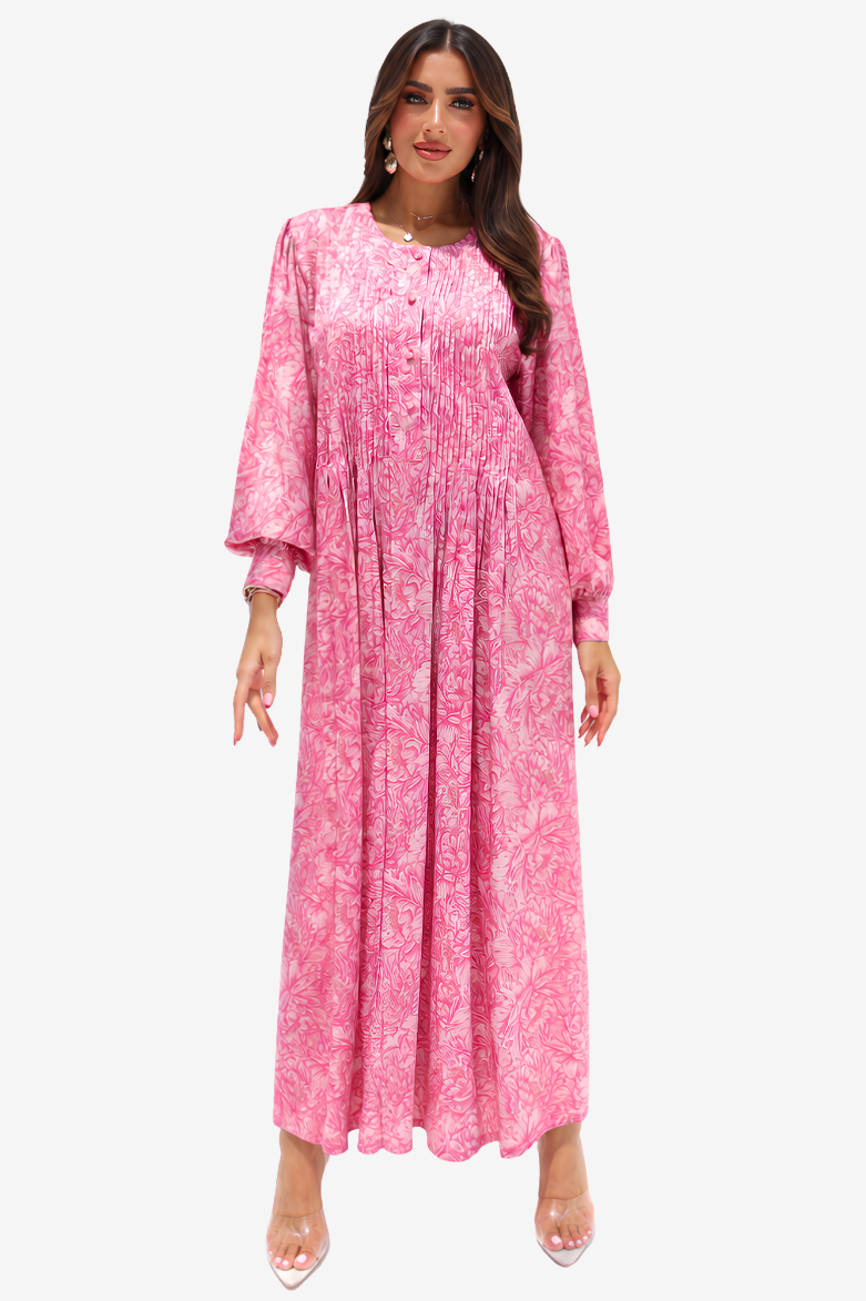 A woman modeling a long-sleeved pink maxi dress with a white abstract pattern, shown against a plain light gray background.