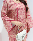 Person wearing a pink floral dress holding a white handbag against a white background
