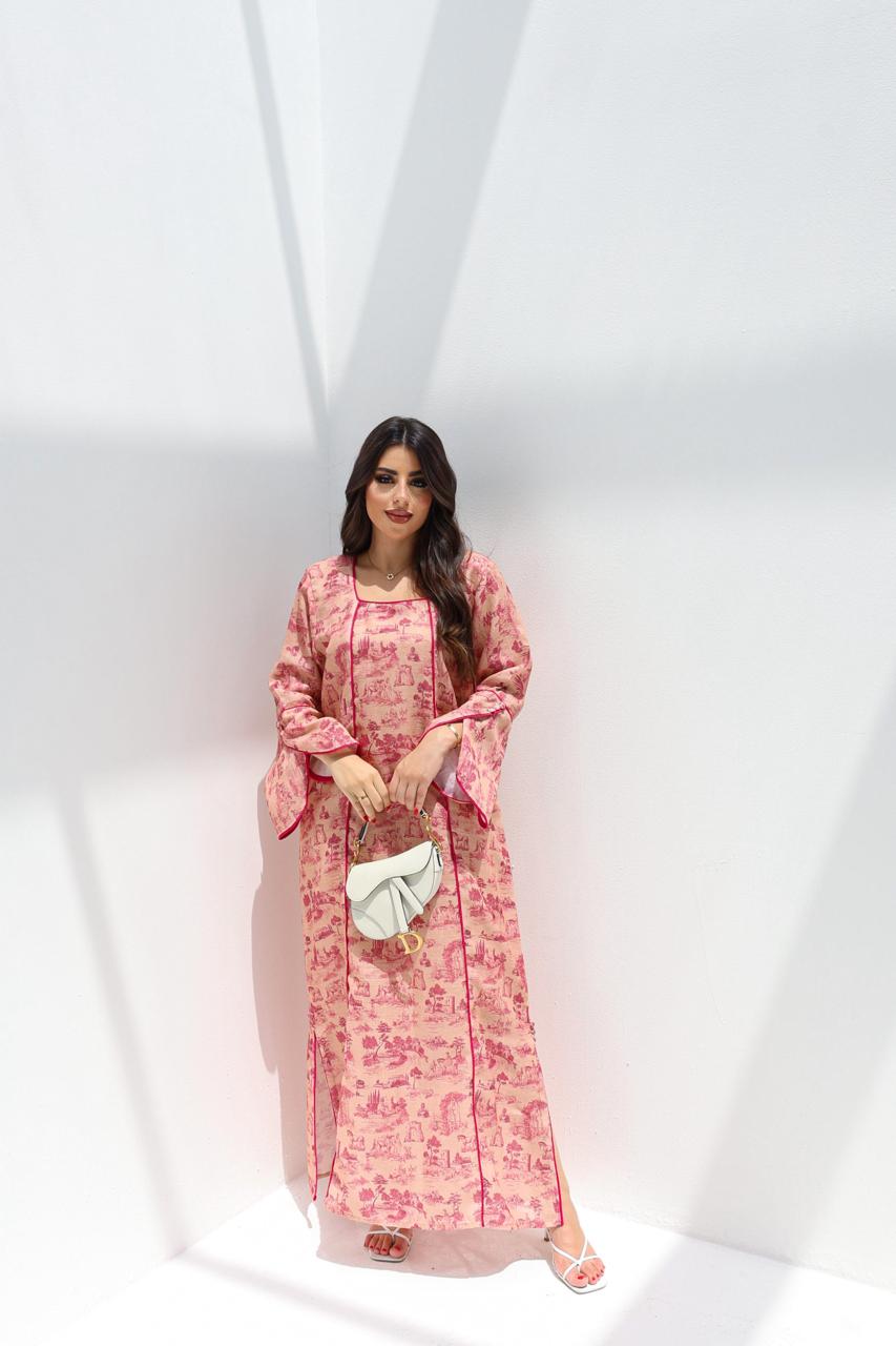 Woman wearing a pink floral dress holding a white clutch against a white background