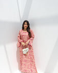 Woman wearing a pink floral dress holding a white clutch against a white background