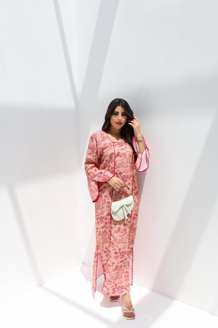 Woman in a pink floral dress holding a white clutch against a white background