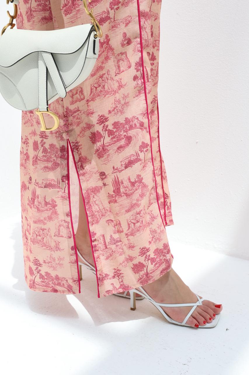 Person wearing pink floral jalabiya with a white background