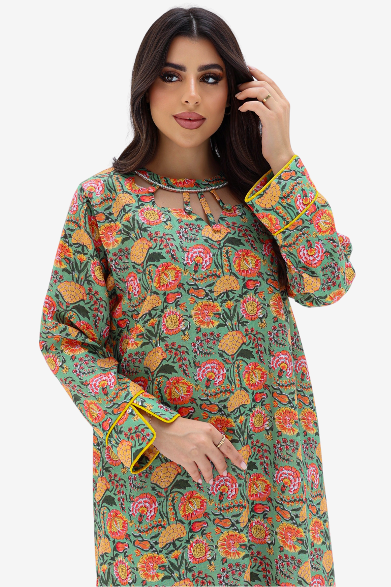 A woman modeling a long-sleeve green kurta with a vibrant multicolor floral print and yellow-gold trim on the cuffs, set against a plain light gray background.