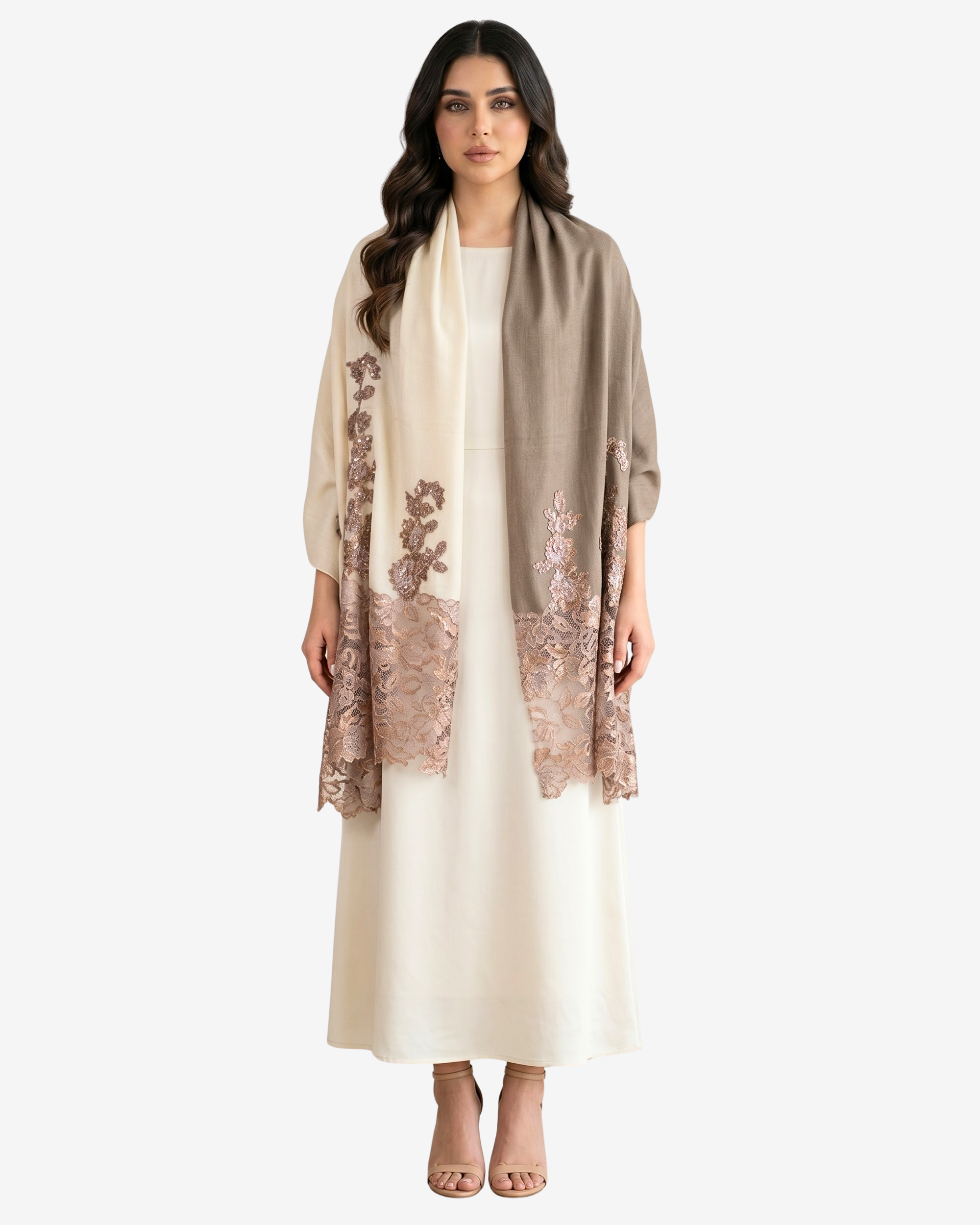 A woman modeling a taupe shawl with rose gold floral lace borders over a cream-colored dress, set against a plain light gray background.