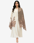 A woman modeling a cream-colored traditional outfit with a draped taupe shawl featuring intricate floral lace embroidery on the edges, set against a plain light gray background.