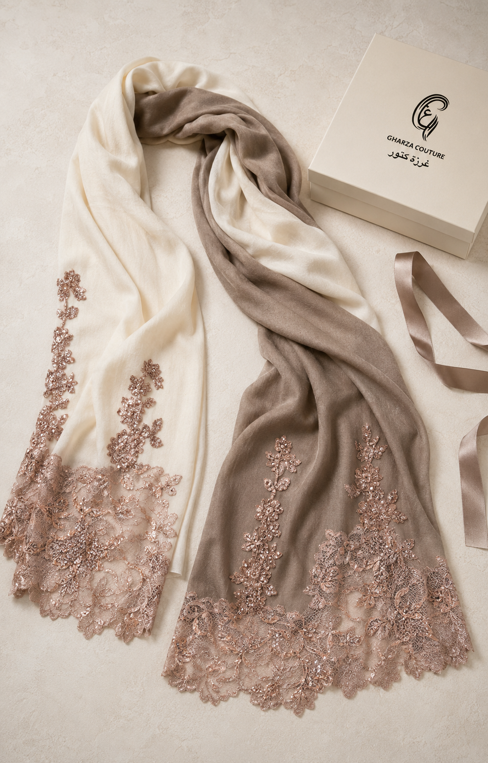 A draped scarf in cream and taupe with rose gold floral lace embroidery, displayed next to a beige gift box on a neutral beige background.