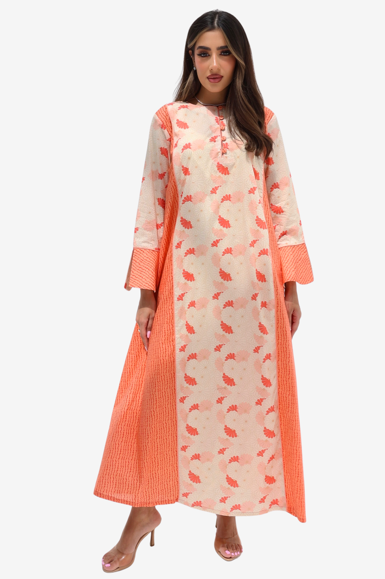 A woman modeling a long cream-colored kurta with a coral-orange leaf print and solid coral-orange striped side panels and cuffs, paired with clear high-heeled sandals against a light gray background.