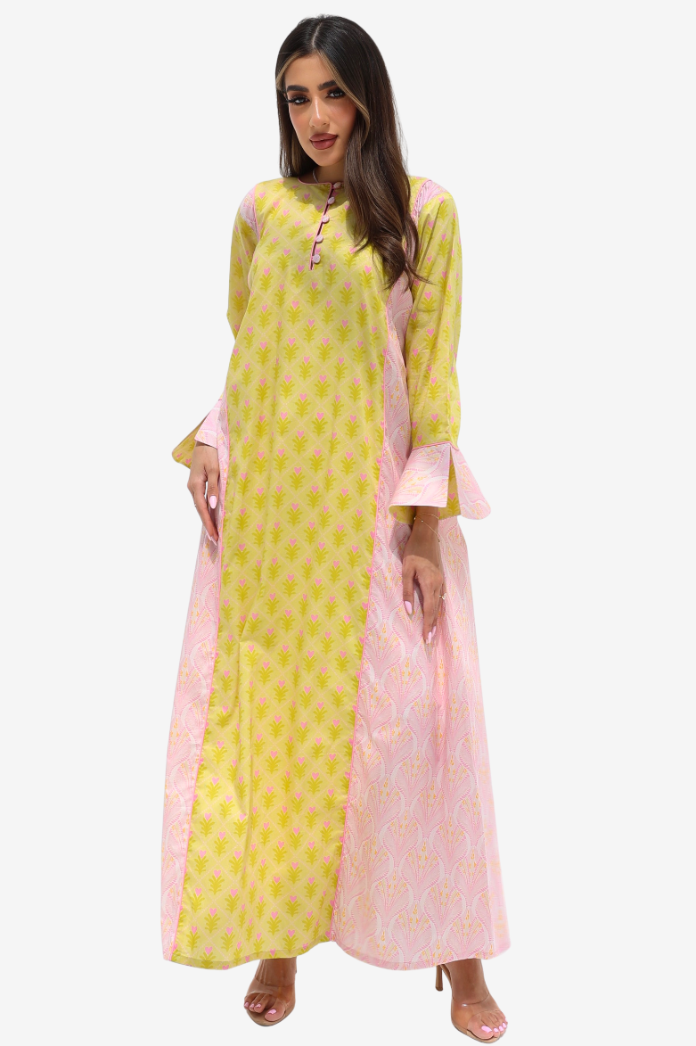 A woman modeling a long-sleeved maxi dress with a split design: one side is coral pink with a small floral print, and the other side is light pink with a dense multicolor floral print. The dress features ruffled bell sleeves and a button-up front.