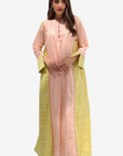A woman modeling a peach-pink and yellow printed traditional outfit with a matching yellow dupatta against a light gray background.