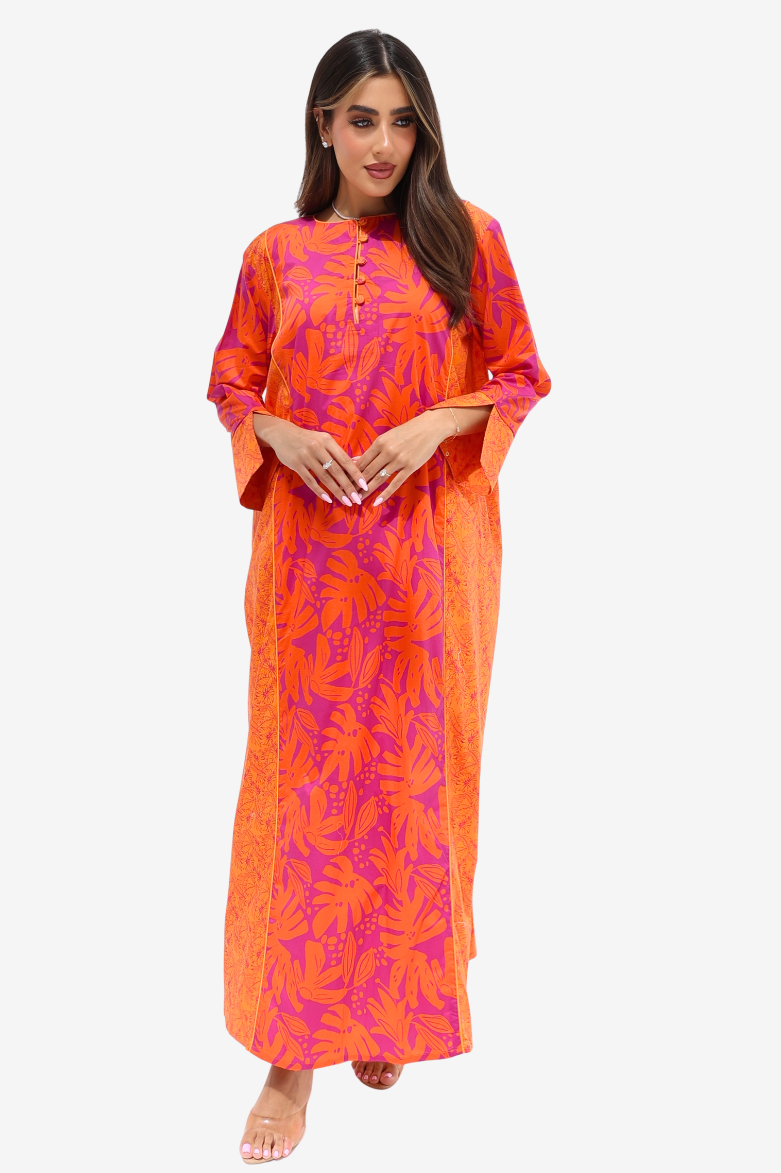 A woman modeling a bright orange and magenta floral print kaftan dress against a plain light gray background.
