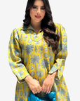 A woman modeling a yellow long-sleeve kurta with a gray botanical pattern, holding a textured blue clutch bag against a light gray background.