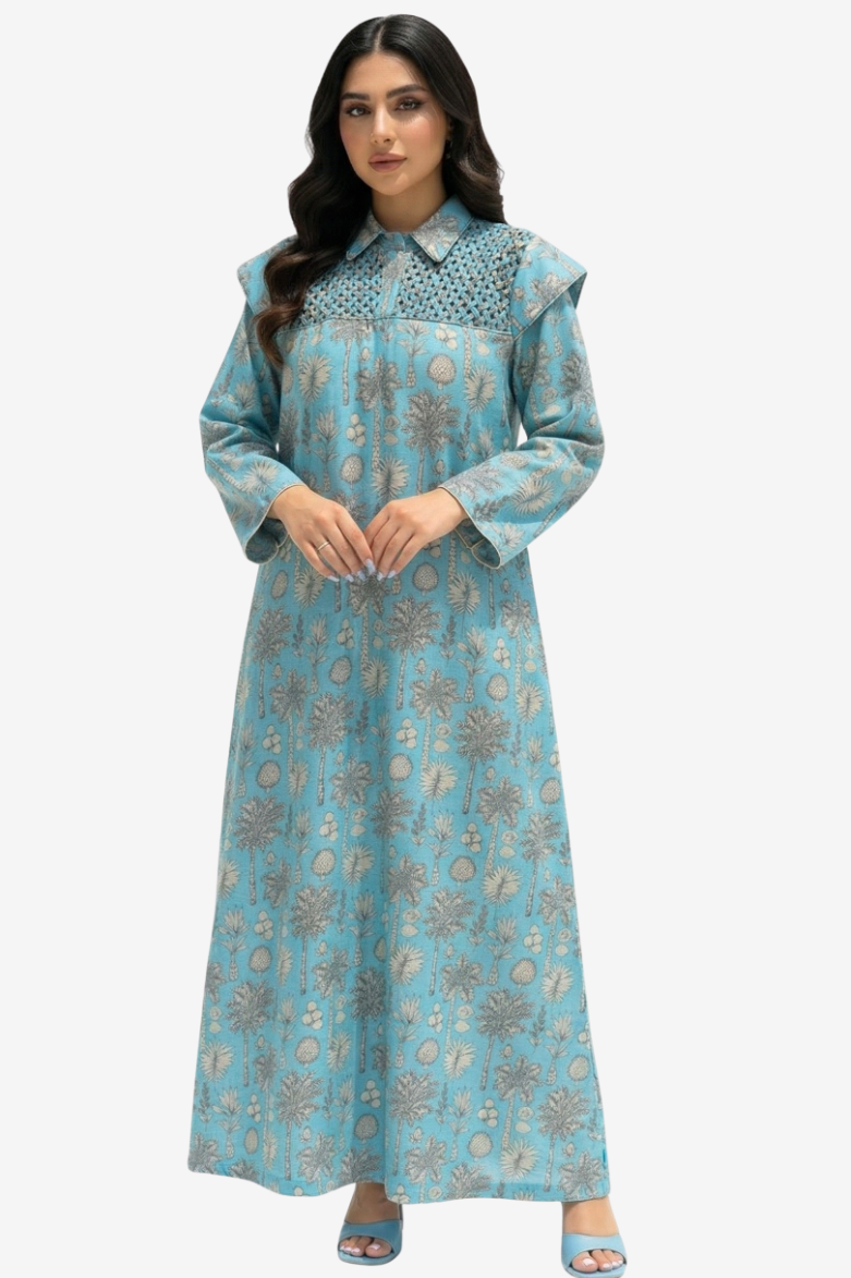 A woman modeling a long-sleeved light blue maxi dress with a detailed floral print and a patterned yoke, set against a plain light gray background.