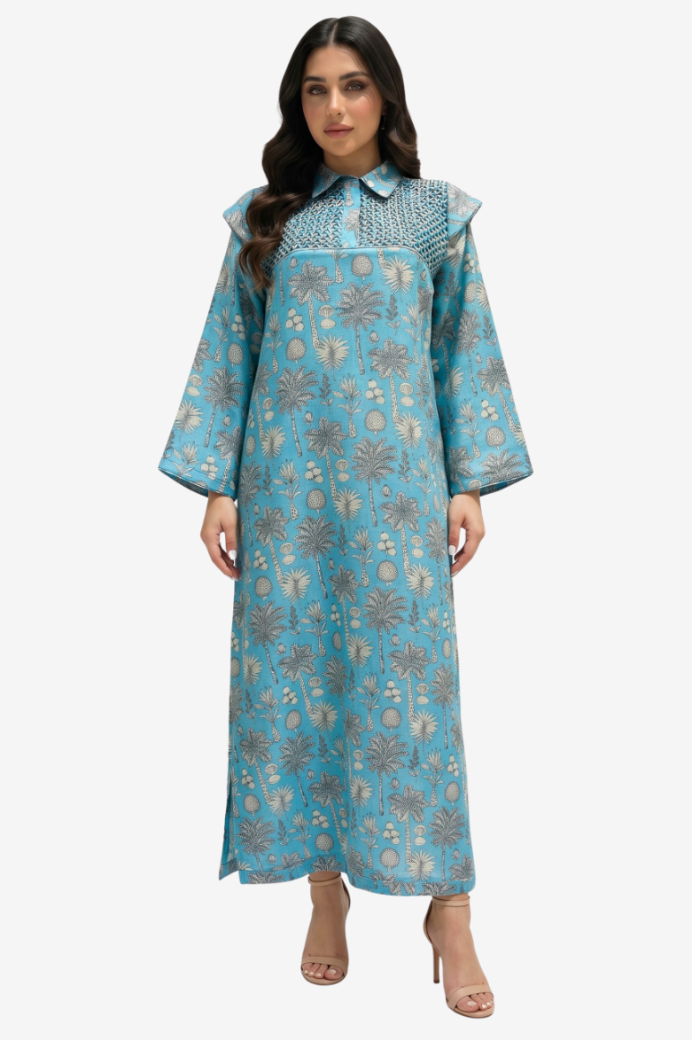 A woman modeling a long-sleeved, floor-length turquoise blue kaftan dress with a beige and gray floral pattern, standing against a light gray background.
