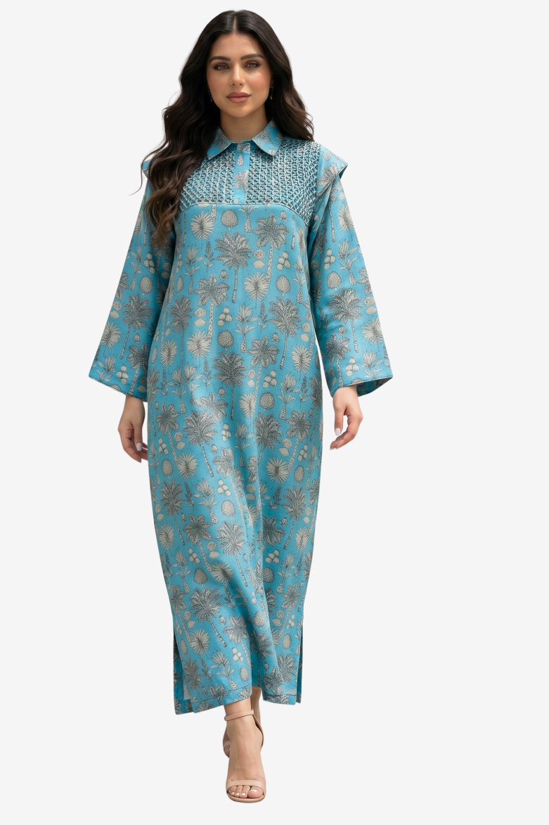 A woman modeling a long-sleeved, collared maxi dress in turquoise blue with a brown and beige floral pattern, set against a plain light gray background.