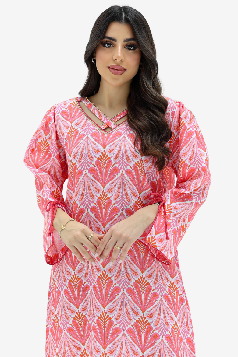 A woman modeling a pink and white patterned long-sleeve dress with a keyhole cutout at the neckline, set against a plain light gray background.