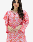 A woman modeling a pink and white patterned long-sleeve dress with a keyhole cutout at the neckline, set against a plain light gray background.