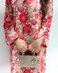 Person wearing a floral dress holding a handbag against a white background