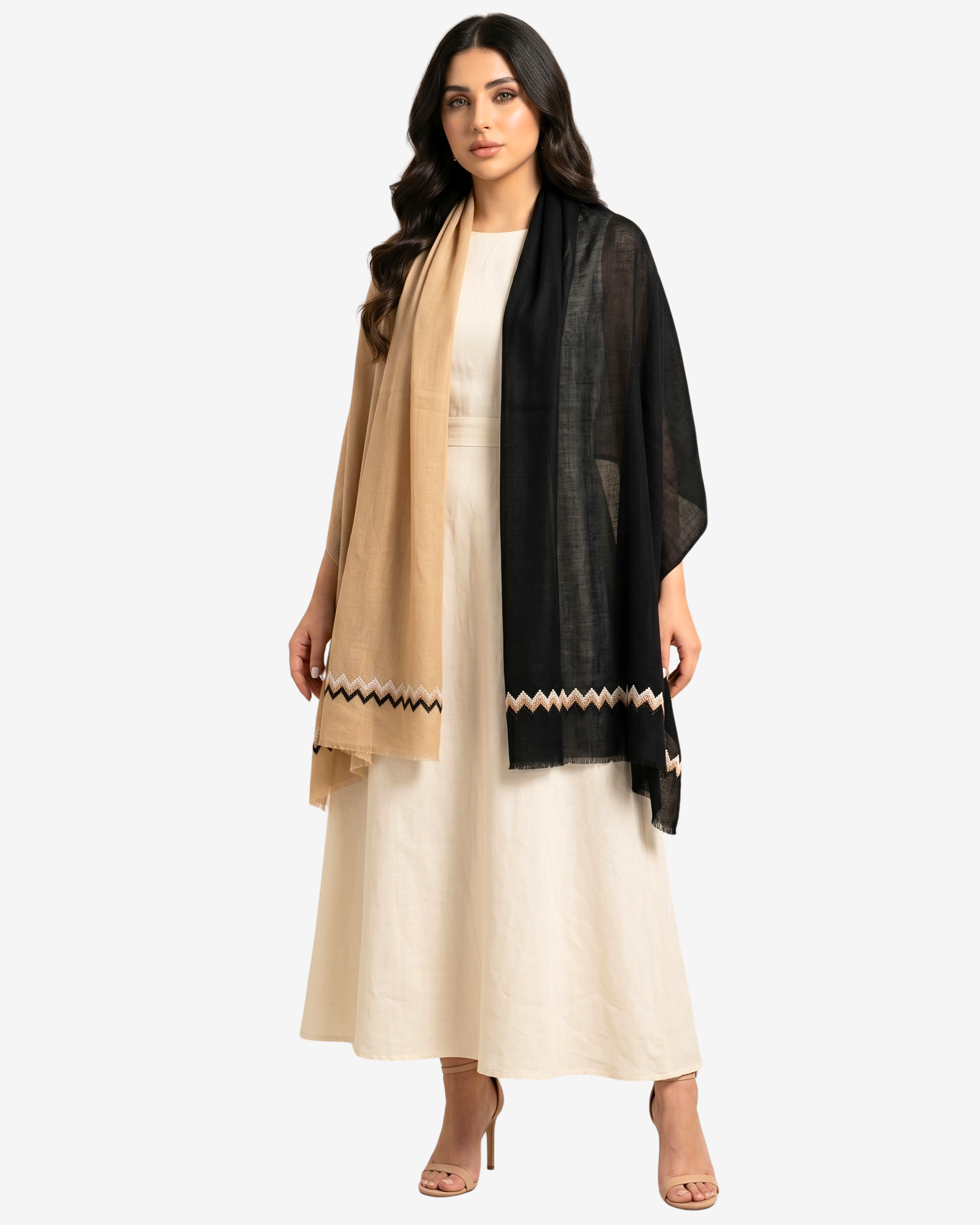 A woman modeling a black sheer shawl with a beige and black zigzag border over a cream-colored dress, set against a plain light gray background.