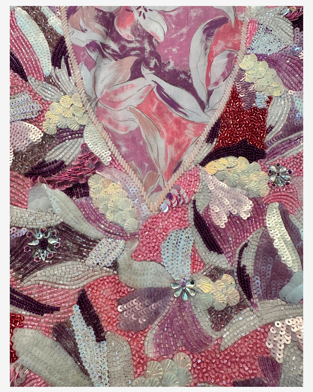 Detailed view of the hand-beaded floral neckline in pink, ivory, plum and red on floral Liberty mukhawar fabric.