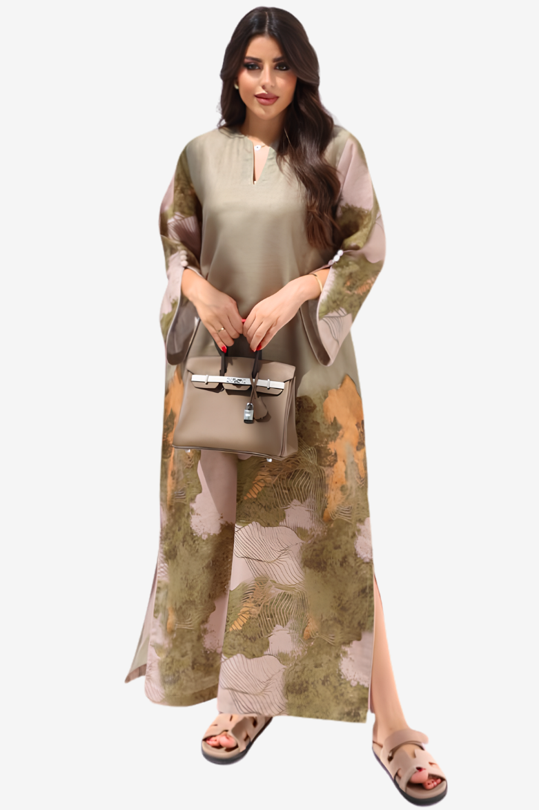 A woman modeling a long-sleeved, knee-length kurta with a split leg, featuring a beige and olive green base with a floral pattern in dusty pink and mustard yellow. She is holding a matching beige handbag and wearing beige sandals against a plain light gray background.