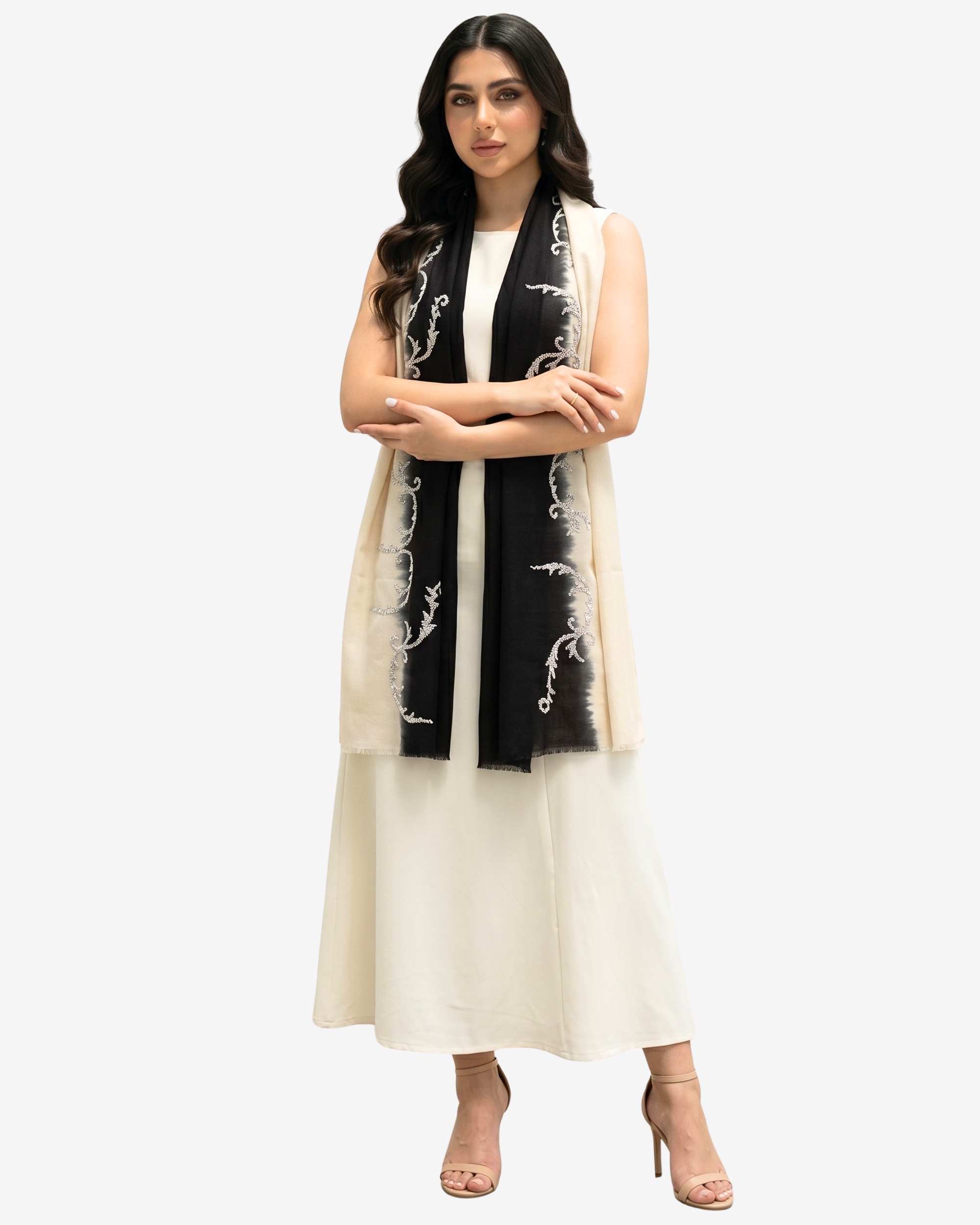 A woman modeling a long cream sleeveless vest over a white dress, accessorized with a black scarf featuring white floral embroidery, against a light gray studio background.